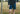 Close up of man wearing midnight leopard lounge shorts by a fence in a field.