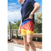 Man on standing with navy blue polo and Sunfish printed (blue red and orange) mesh shorts. 