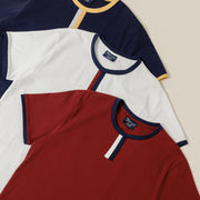 Three vintage ringer shirts in navy, white, and red on a beige background
