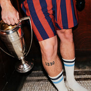 Man holding trophy in court stripe lounge shorts and tech varsity socks.