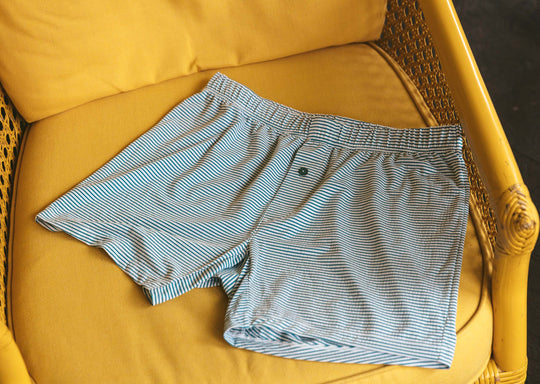 Pair of green striped slim fit boxers laid flat on a yellow chair. 