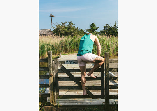 Man in green tank top and tech varsity slim fit boxers jumping over fence
