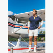 Man standing in front of plane wearing Navy vintage ringer and cream lounge shorts