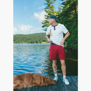 Man standing on lake dock wearing white vintage ringer tee shirt and burgundy lounge shorts.