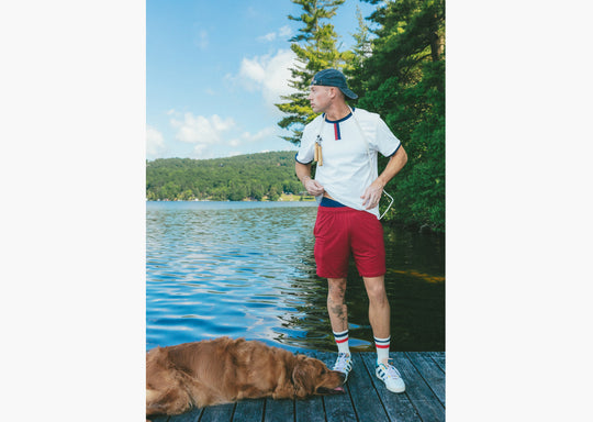 Man standing on lake dock wearing white vintage ringer tee shirt and burgundy lounge shorts.