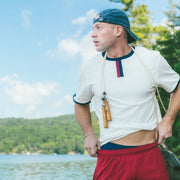 Man standing on lake dock wearing white vintage ringer tee shirt and burgundy lounge shorts.