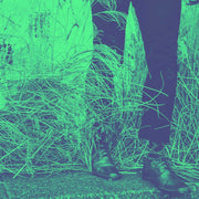 Man wearing dress shoes and dress pants in a thicket of flowers.