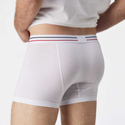 Close up back view of man wearing white boxer brief with blue and red stripe on label.