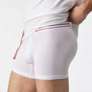 Close up side view of man wearing white boxer brief with blue and red stripe on label.