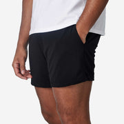 Close up side view of mean wearing black lounge short with hand in pocket.