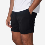 Close up of man wearing black lounge short with hand in pocket.