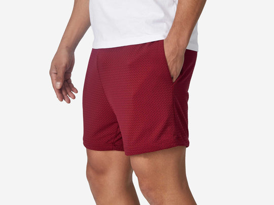 Close up side view of mean wearing burgundy lounge short with hand in pocket.