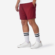 Side view shot of man wearing burgundy lounge short with hand in pocket.