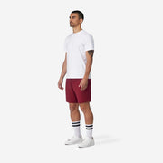 Full body side view shot of man wearing burgundy lounge short with hand in pocket.