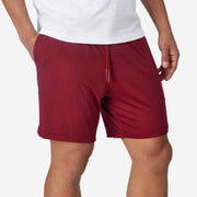 Close up shot of man wearing burgundy lounge short with hand in pocket.