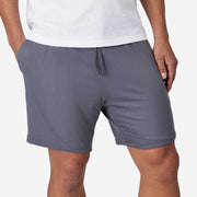 Close up front view of man wearing grey mesh short with hand in pocket.