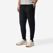 Front side view of man wearing black lounge pants with hand in pocket.