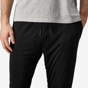 Close up front view of man wearing black lounge pants with hand in pocket.