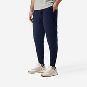 Close up side view of man wearing navy blue lounge pant with hand in pocket. 