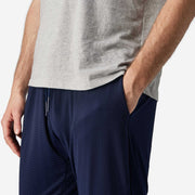 Close up side view of man wearing navy blue lounge pant with hand in pocket. 