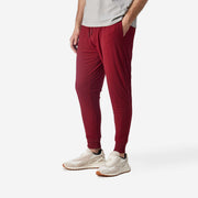 Side view of man wearing burgundy lounge pants with hand in pocket.