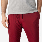 Close up front view of man wearing burgundy lounge pants with hands in pocket.