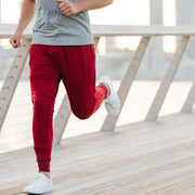 Man running on boardwalk in burgundy lounge pants.