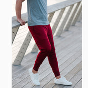 Man leaning against the railing in burgundy lounge pants from a different angle with grey t shirt.