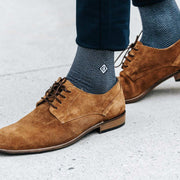 Man wearing navy blue herringbone monogram socks paired with brown dress shoes.