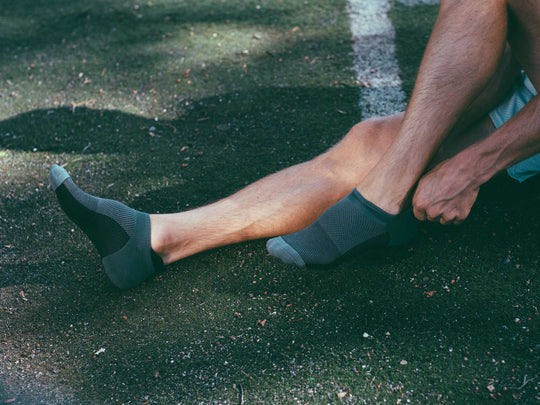 Man putting on darkhorse athletic socks.