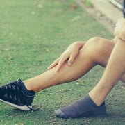 Man sitting on a lawn with sneakers and darkhorse athletic socks.