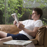 Man reading newspaper inside wearing lounge shorts with varsity T embroidery.