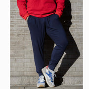 Man wearing cloud pants leaned against a brick wall.