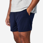 4" Navy Pocket Lounge Short on model with hands in pocket on grey background.