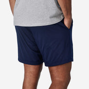 Man wearing lounge shorts with hands in pockets back view.