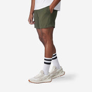 4" Matte Olive Pocket Lounge Short on model side view hands in the pocket.