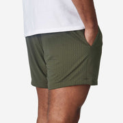 4" Matte Olive Pocket Lounge Short on model back view on grey background.