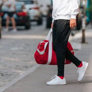 Man wearing black lounge pants and white hoodie on the sidewalk.