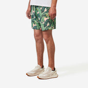 Front side view of man wearing pink mesh lounge shorts with palm leafs printed in green.