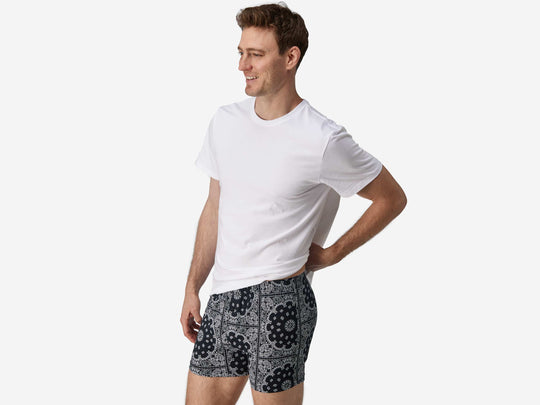 Full body side view of man wearing black bandana slim fit boxers & white t-shirt.