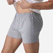 Close up side view of man wearing heather grey slim fit boxers lifting up his white t-shirt.