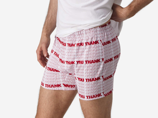 Close up side view of man wearing red & white printed "thank you" slim fit boxers & white t-shirt.
