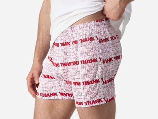 Close up side view of man wearing red & white printed "thank you" slim fit boxers & white t-shirt.