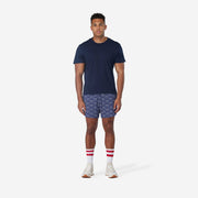 Full body front view of man wearing blue lounge shorts with sunrise pattern.