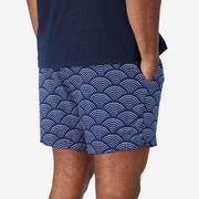 Back view of man wearing blue lounge shorts with sunrise pattern.