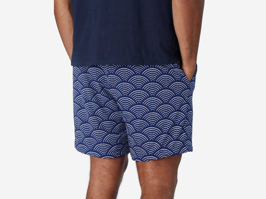 Back view of man wearing blue lounge shorts with sunrise pattern.