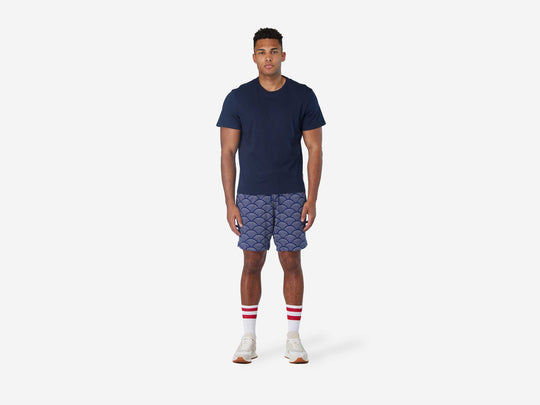 Full body font view of man wearing blue lounge shorts with sunrise pattern.