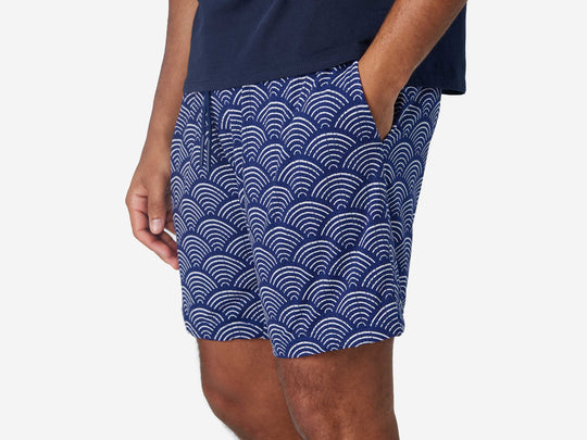 Close up of man wearing blue lounge shorts with sunrise pattern.