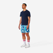 Full body side view of man wearing blue and white wave printed lounge shorts.