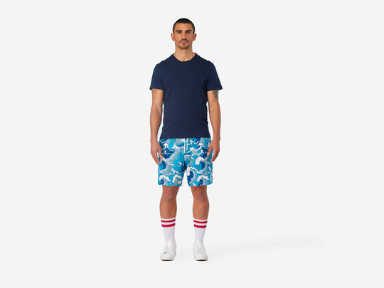 Full body front view of man wearing blue and white wave printed lounge shorts.
